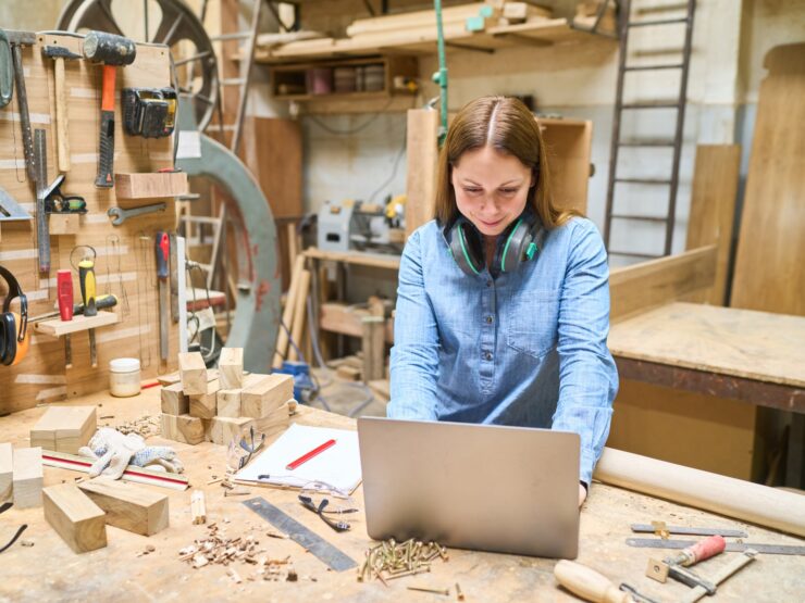 Frau in einer Werkstatt und arbeitet an einem Laptop